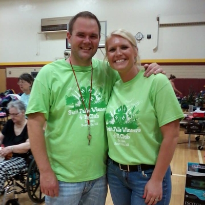 Jim Ostlie and a fellow 4-H volunteer wearing green 4-H shirts standing in a gym.